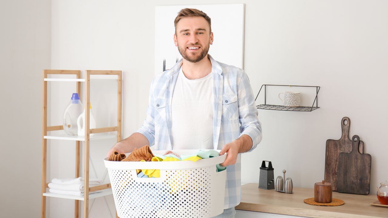 man holding a white laundry basket full of clothes