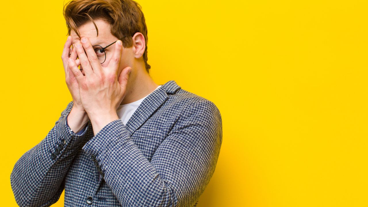 man feeling embarrassed, has hands covering his face