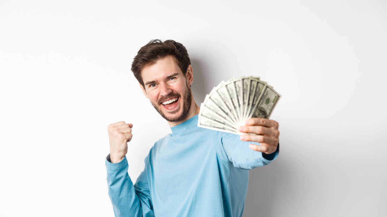 happy man holding money in one hand and making fist with other