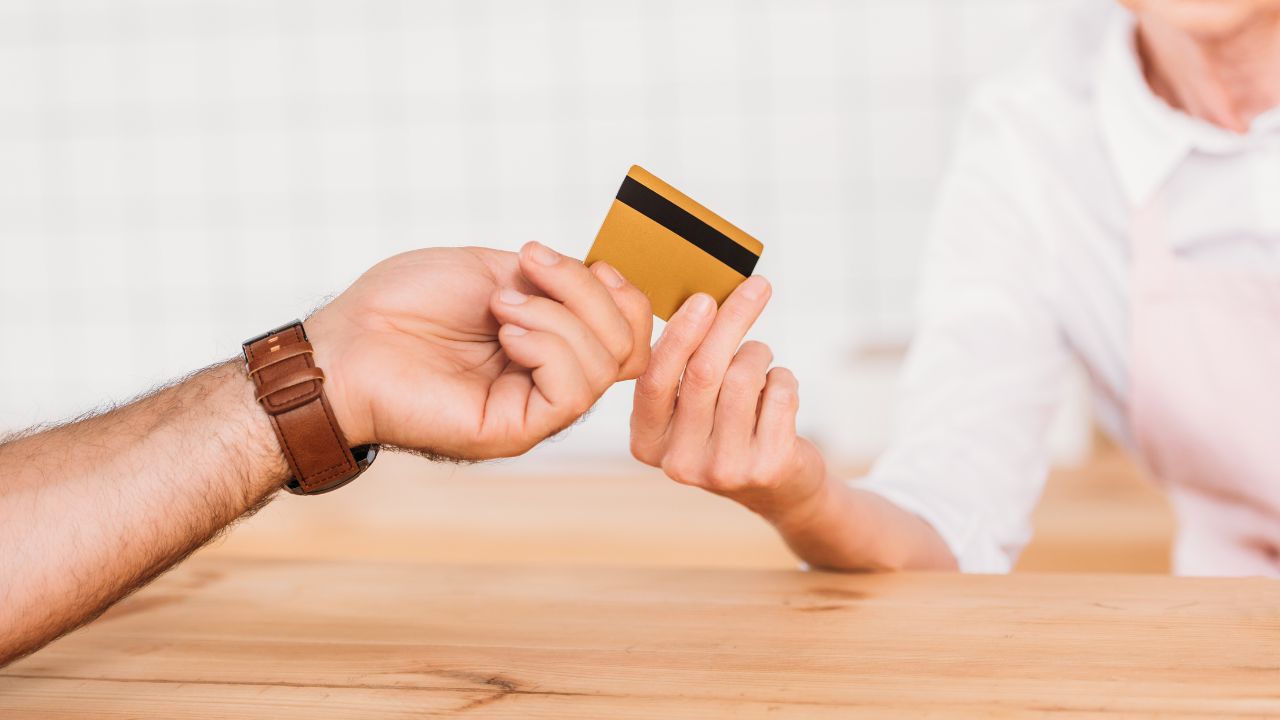 a man's hand giving woman restaurant worker a credit card