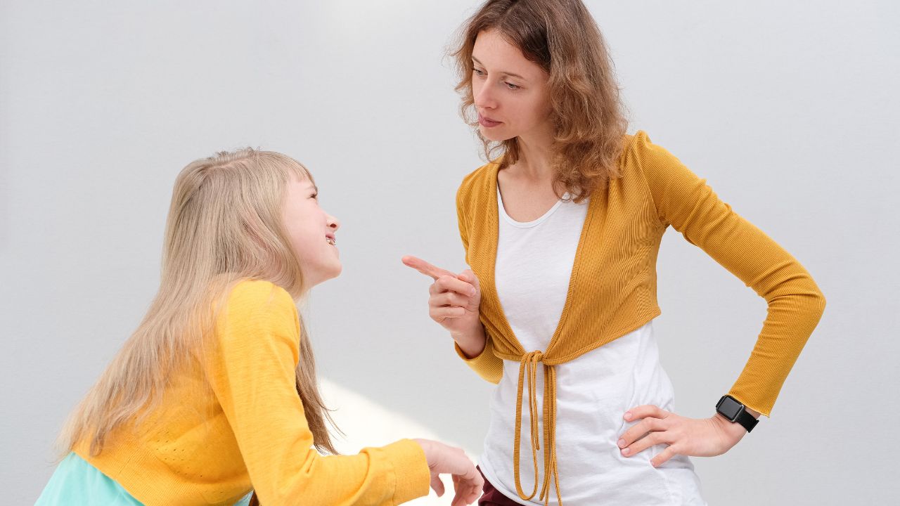 mom pointing finger at her daughter while talking to her sternly
