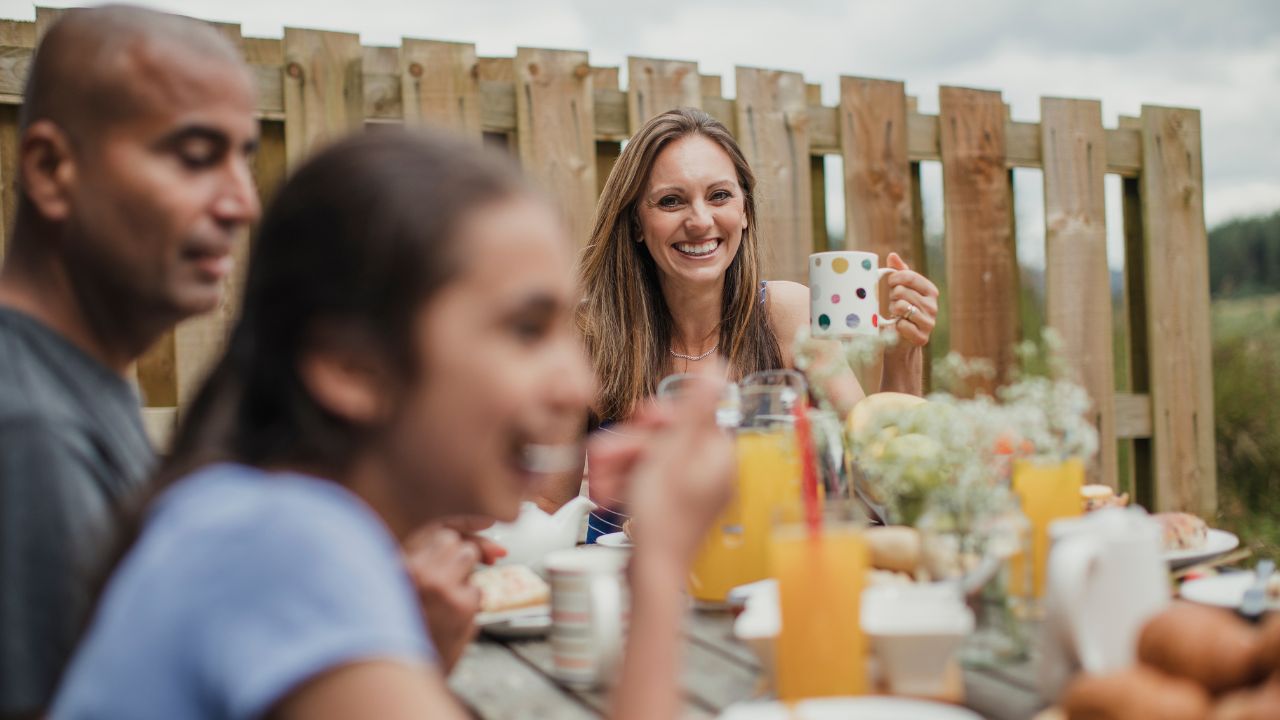 mother holding a coffee mug and smiling while having breakfast with family