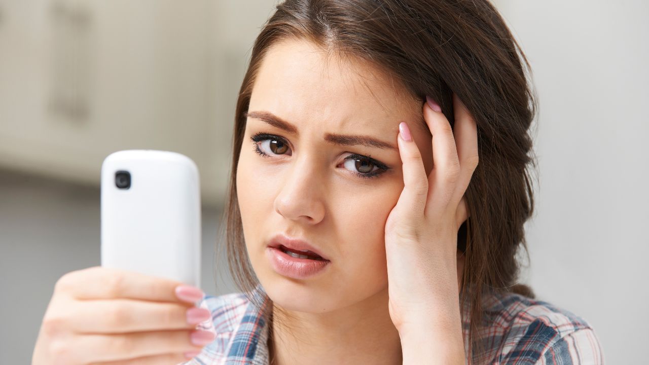 teenage girl holding cell phone looking upset. cyber bulling, she's being cyber bullied.