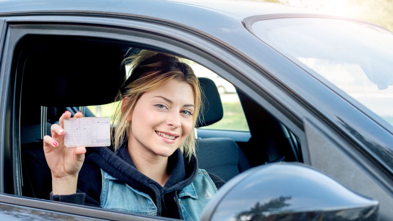 teenager holding driver's license in a car