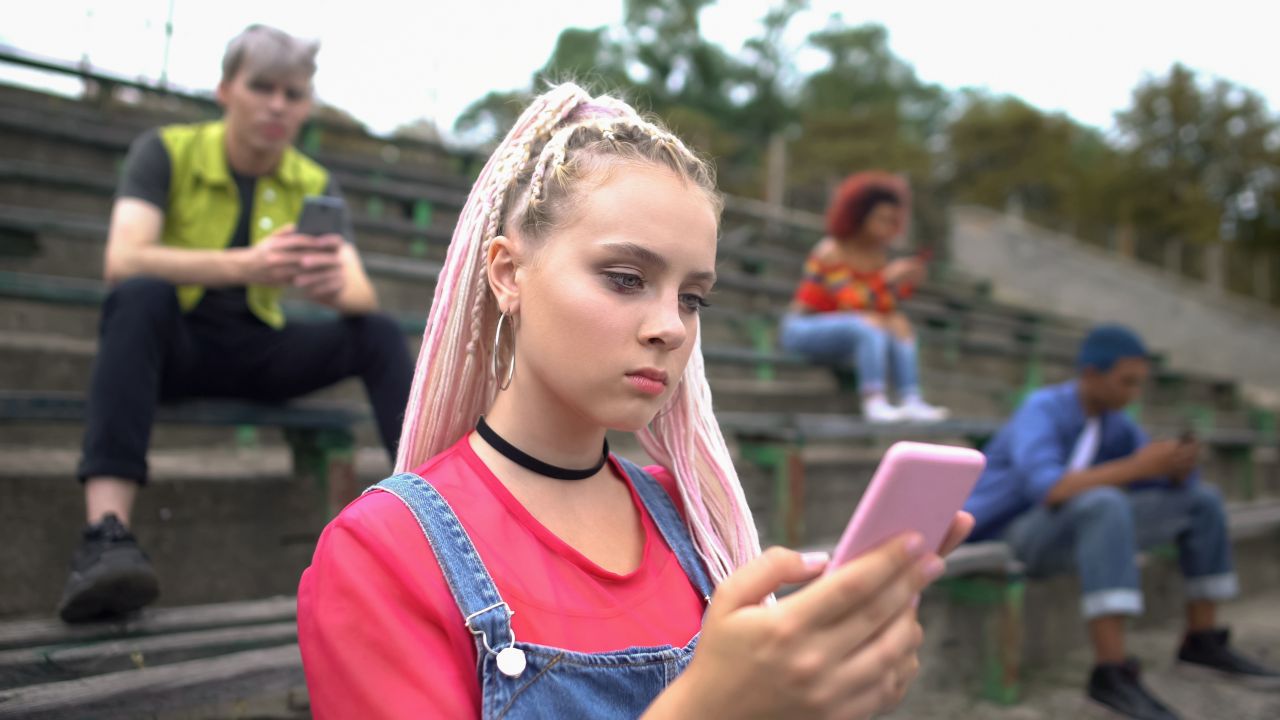 teenagers on their cell phones, sitting separately