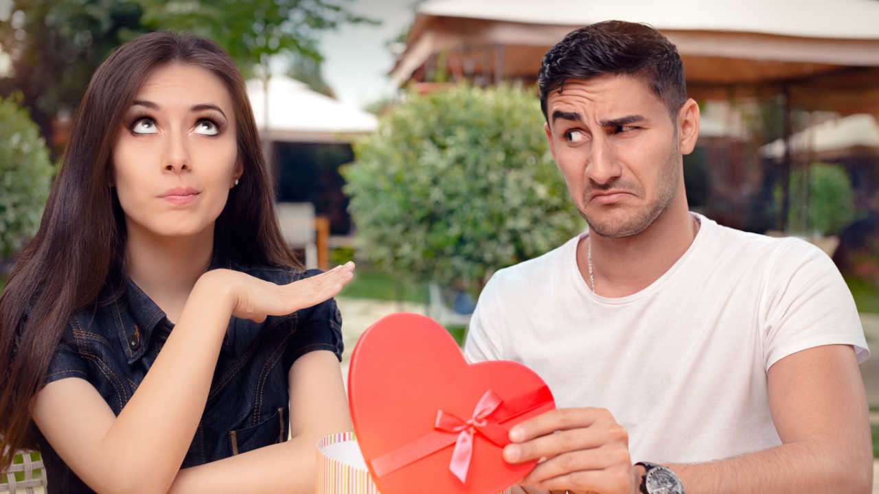 woman doesn't like man who is giving her a heart shaped box of chocolates, bad date.