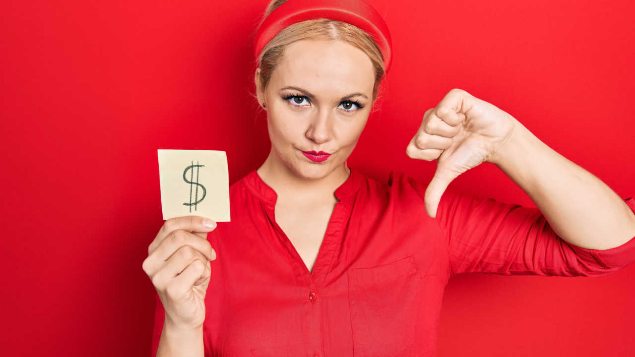 woman holding paper with dollar sign, money, and thumbs down