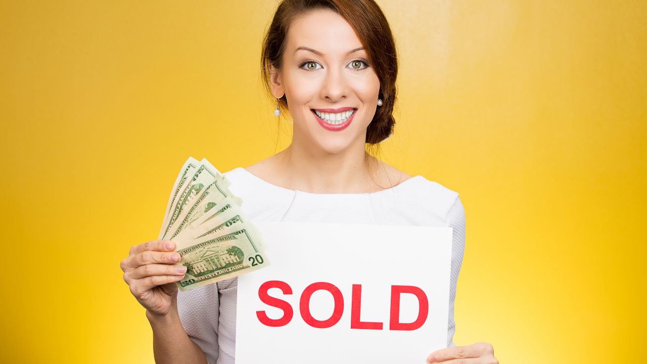 woman holding a sold sign and cash