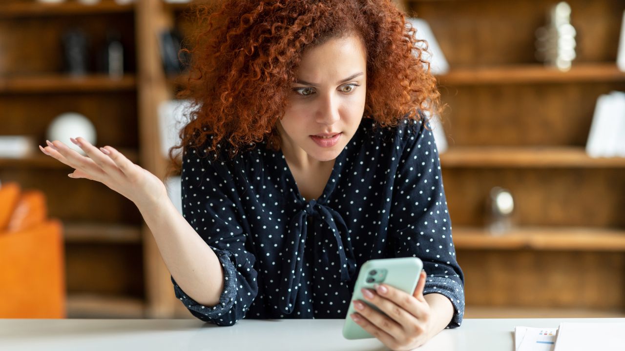 woman looking at her cellphone looking annoyed