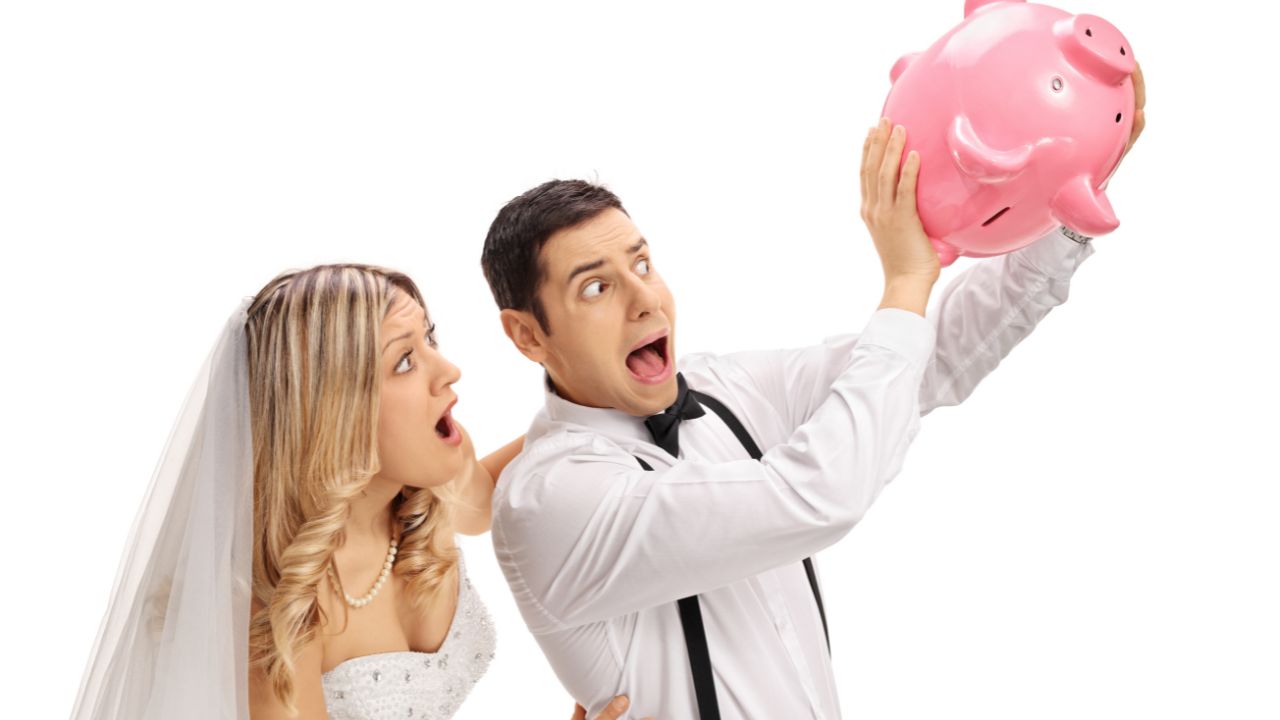 bride and groom looking at piggy bank that groom is holding