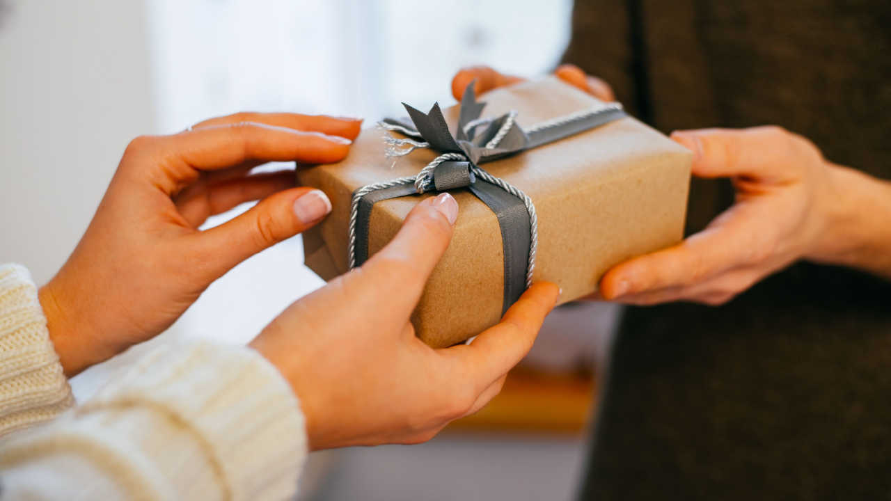 man and woman hands on a wrapped gift