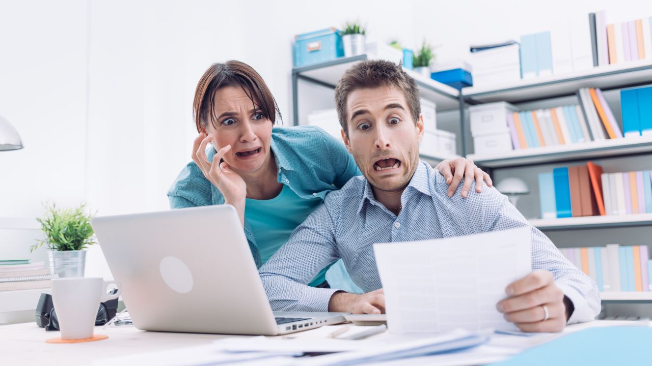 man and woman looking at a paper or document and looking shocked or surprised