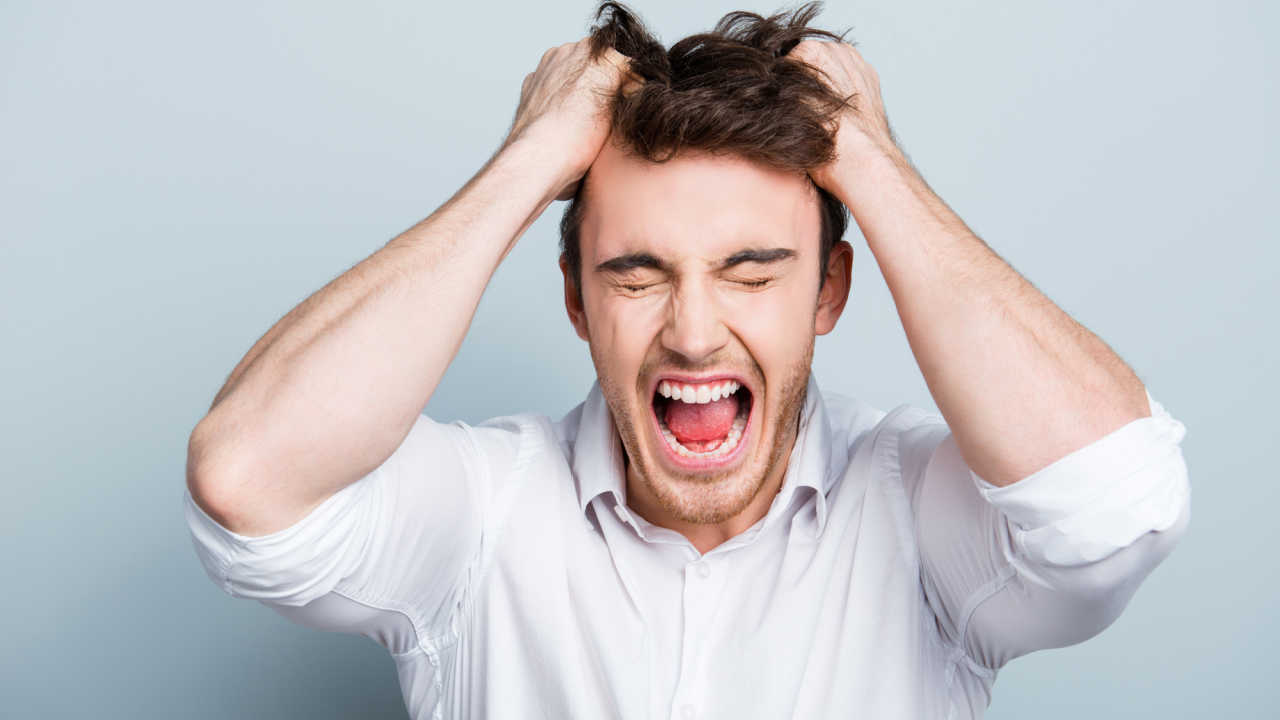 man has hands in hair feeling angry and frustrated