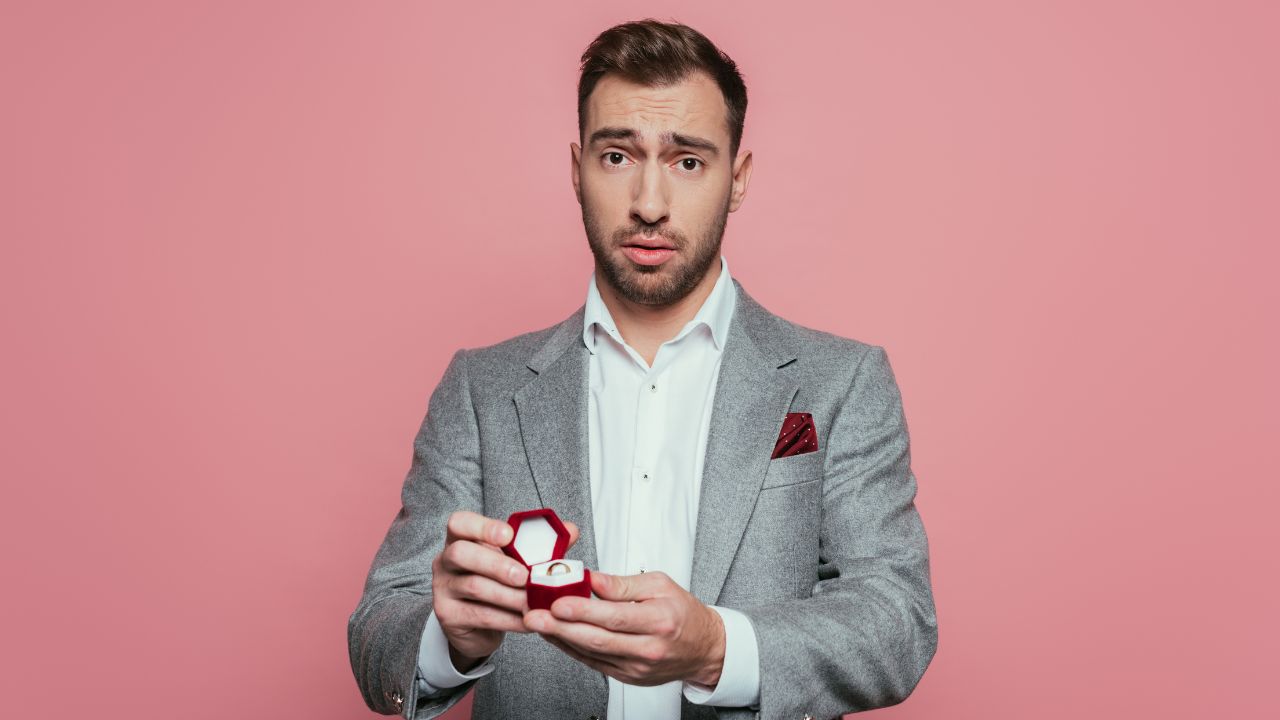 man holding engagement ring looking confused