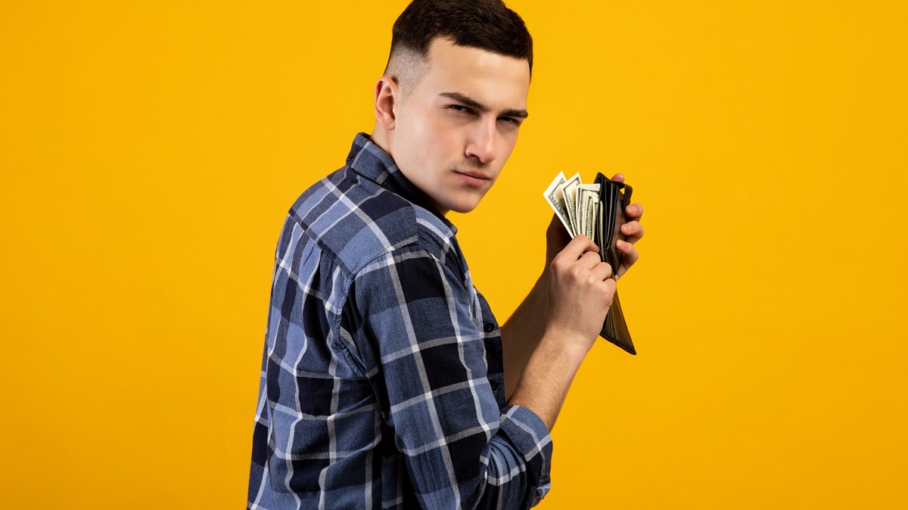 man putting money in his wallet, looking suspicious or sneaky