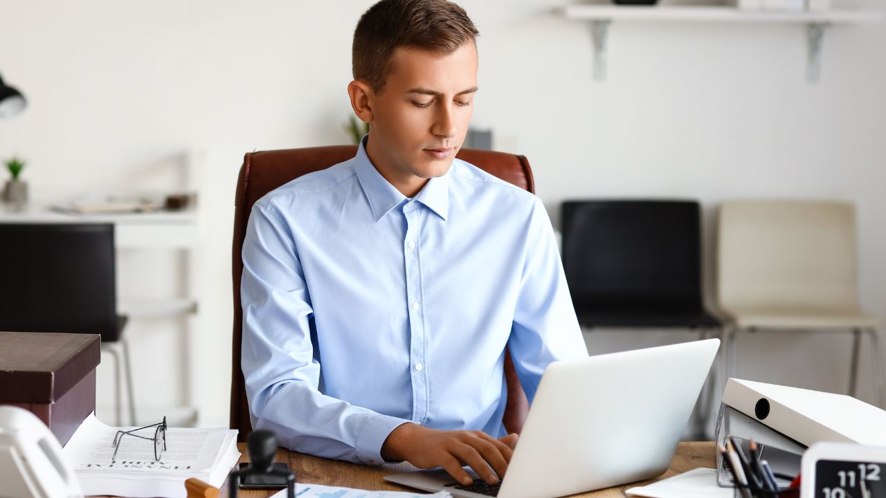 man sitting at his desk working on a laptop