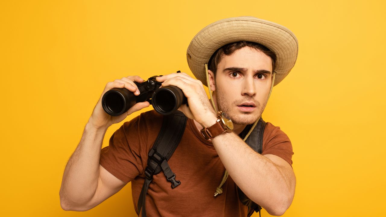 man tourist wearing sunhat, binoculars and backpack