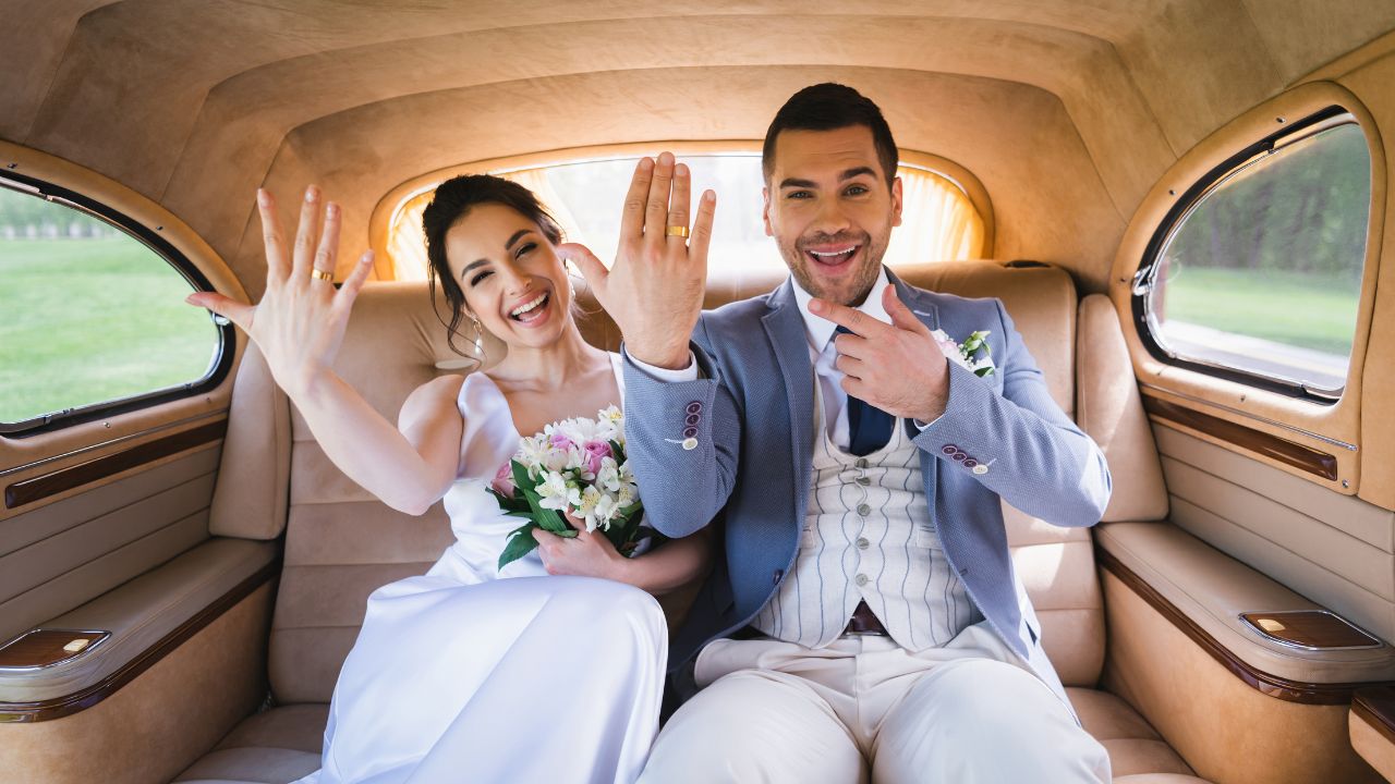 married couple sitting in back of car showing their wedding rings off