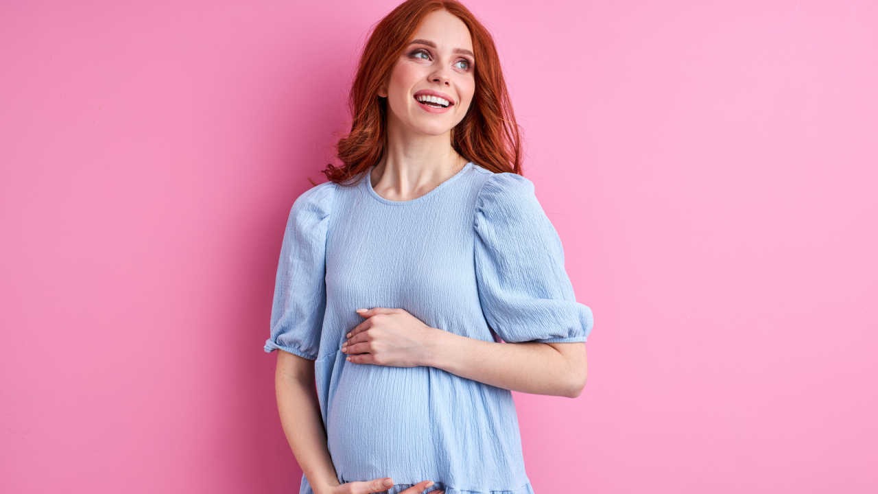 pregnant woman holding her belly and looking happy
