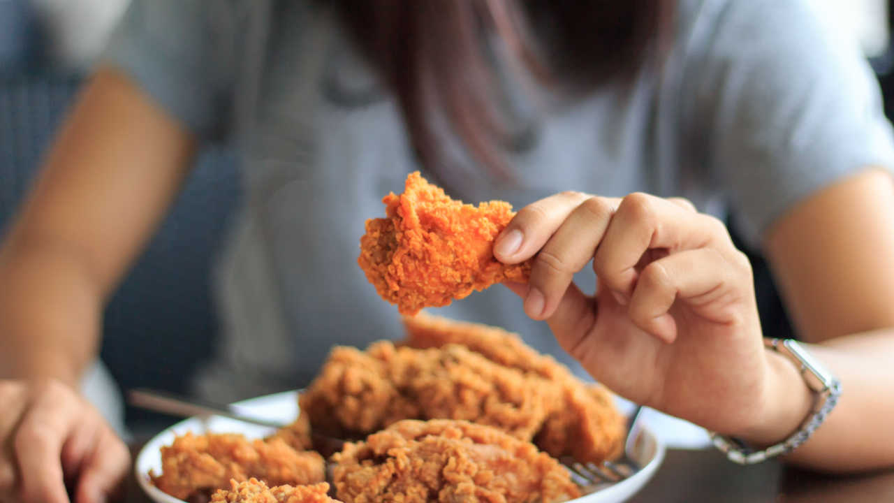 woman's hand picking up a chicken nugget or fried chicken off a plate