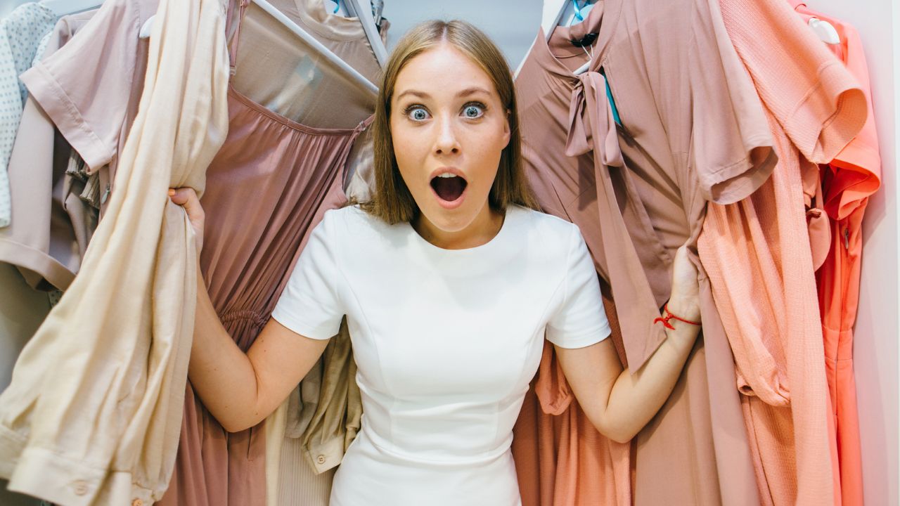 women looking happy standing between a clothes rack