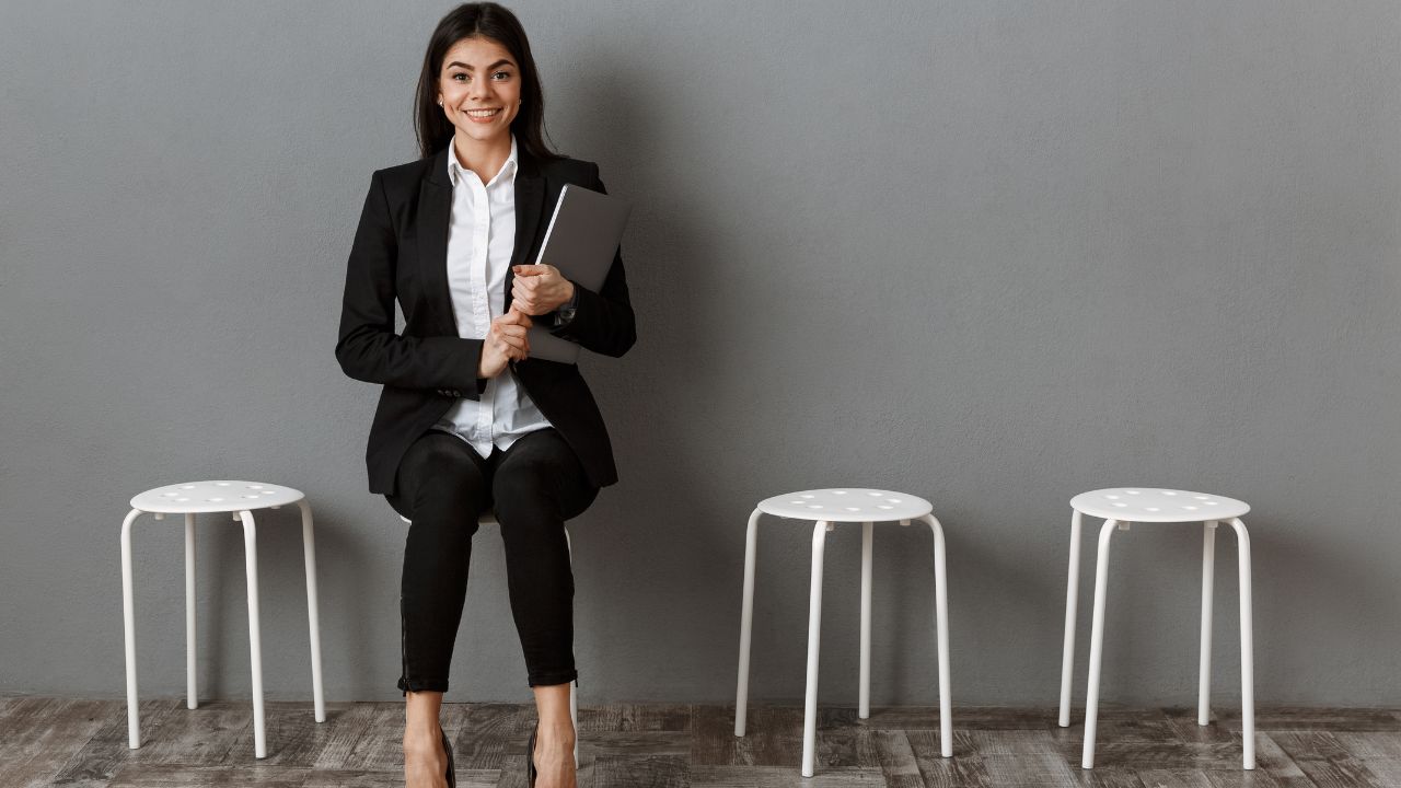 woman waiting, sitting on a stool and wearing a business suit