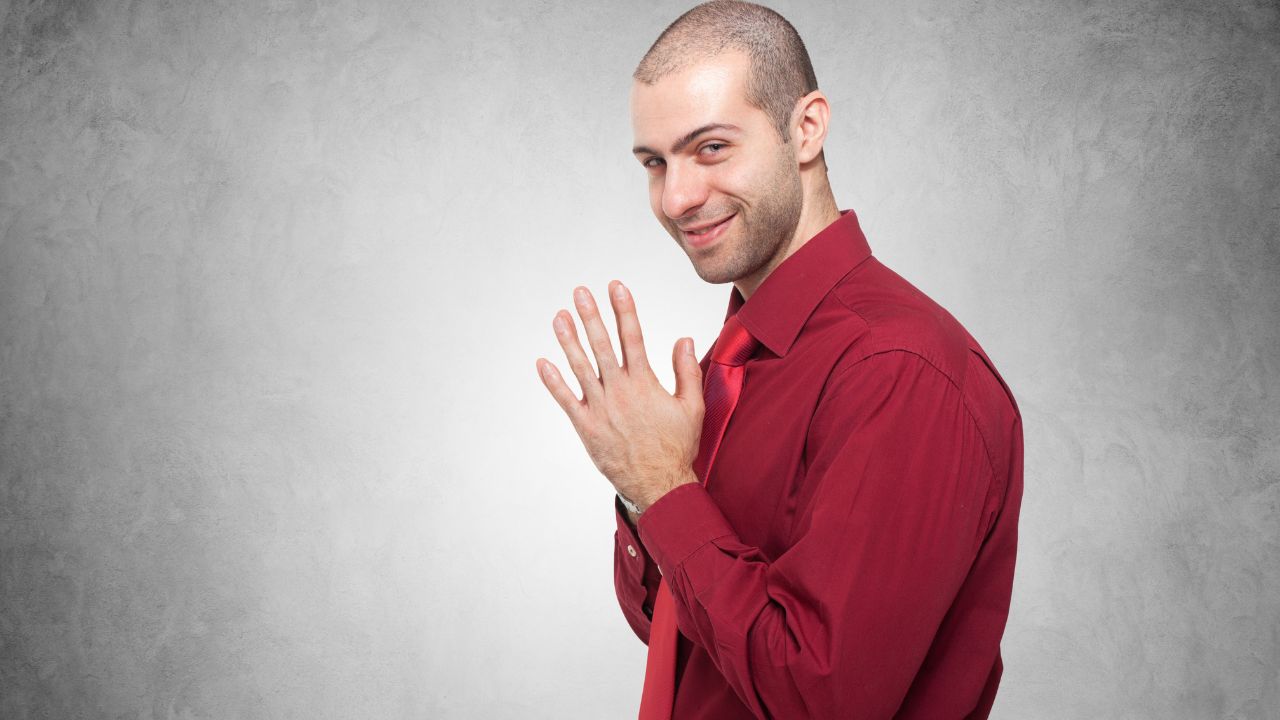 man with mischievous smile and hands together