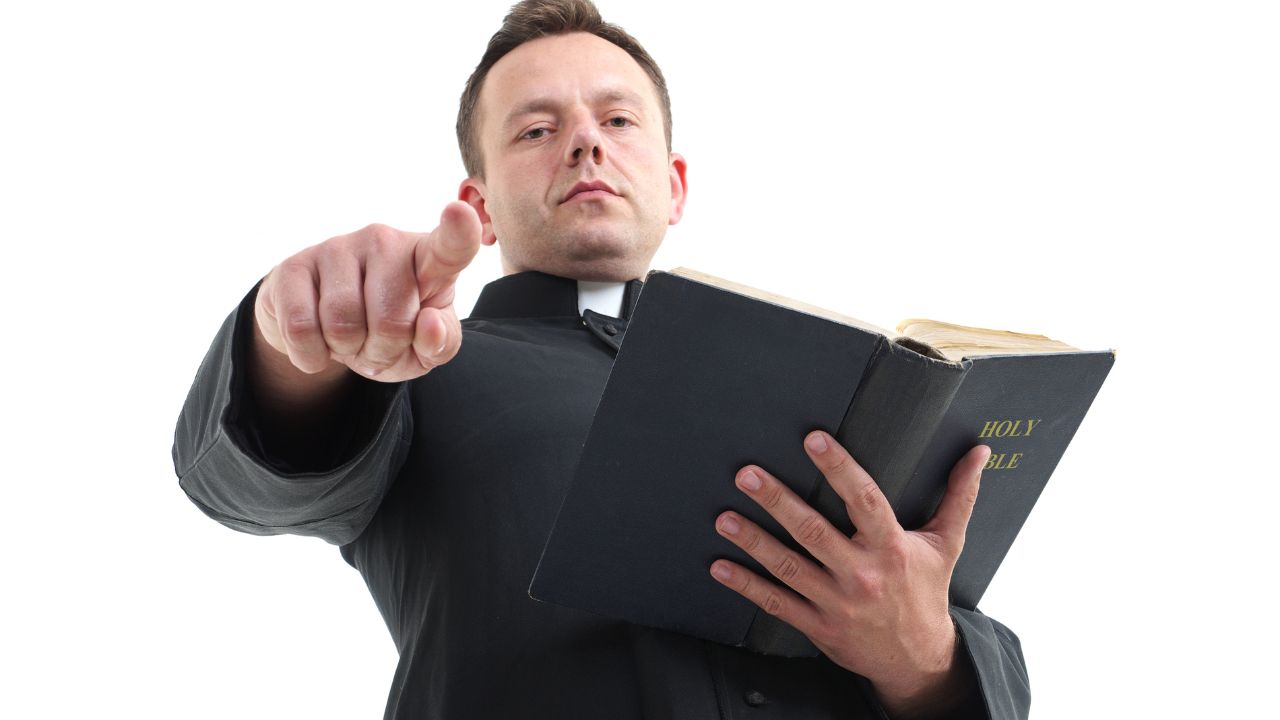 man wearing priest color holding the bible and pointing