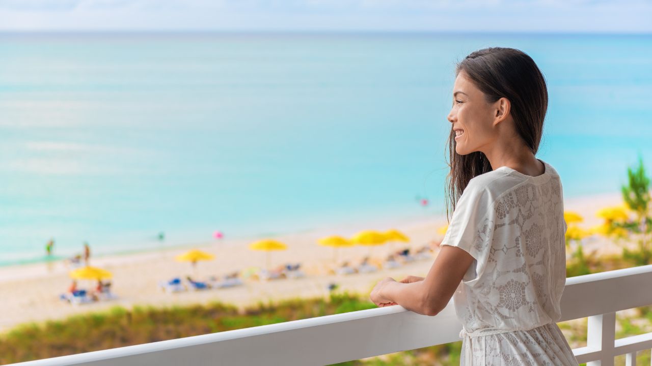 woman looking over balcony at ocean view
