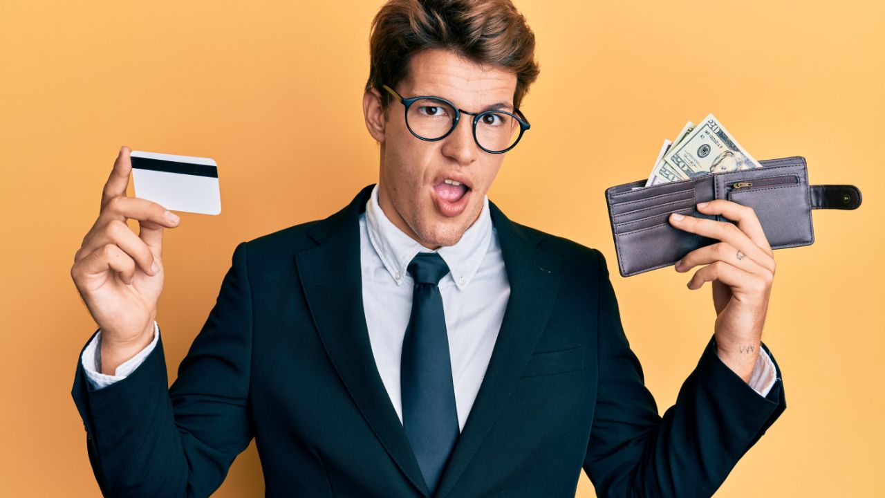 man holding wallet with money in one hand and credit card in the other