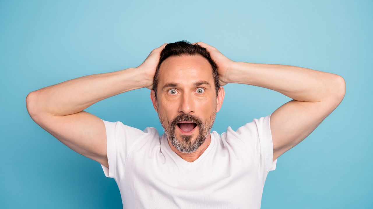 man with hands on head looking overwhelmed and confused