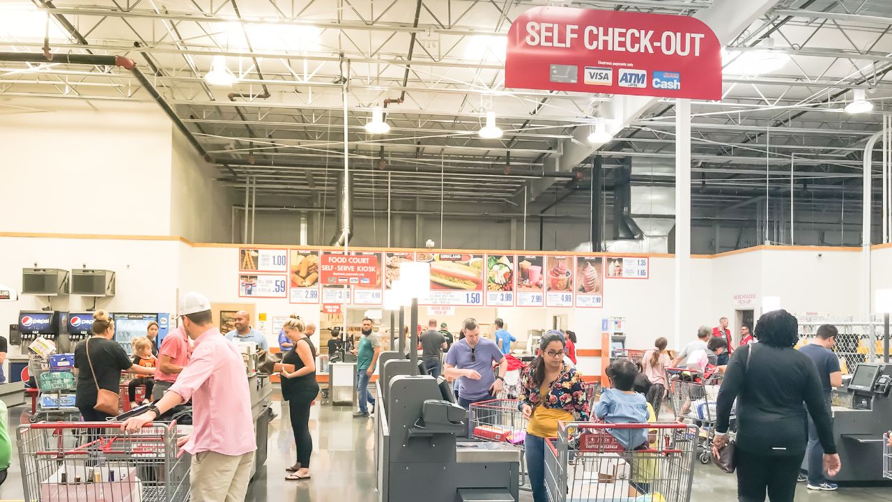 people lined up with grocery carts in a grocery store