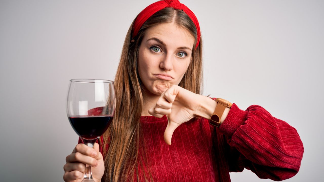 woman holding wine glass and giving a thumbs down