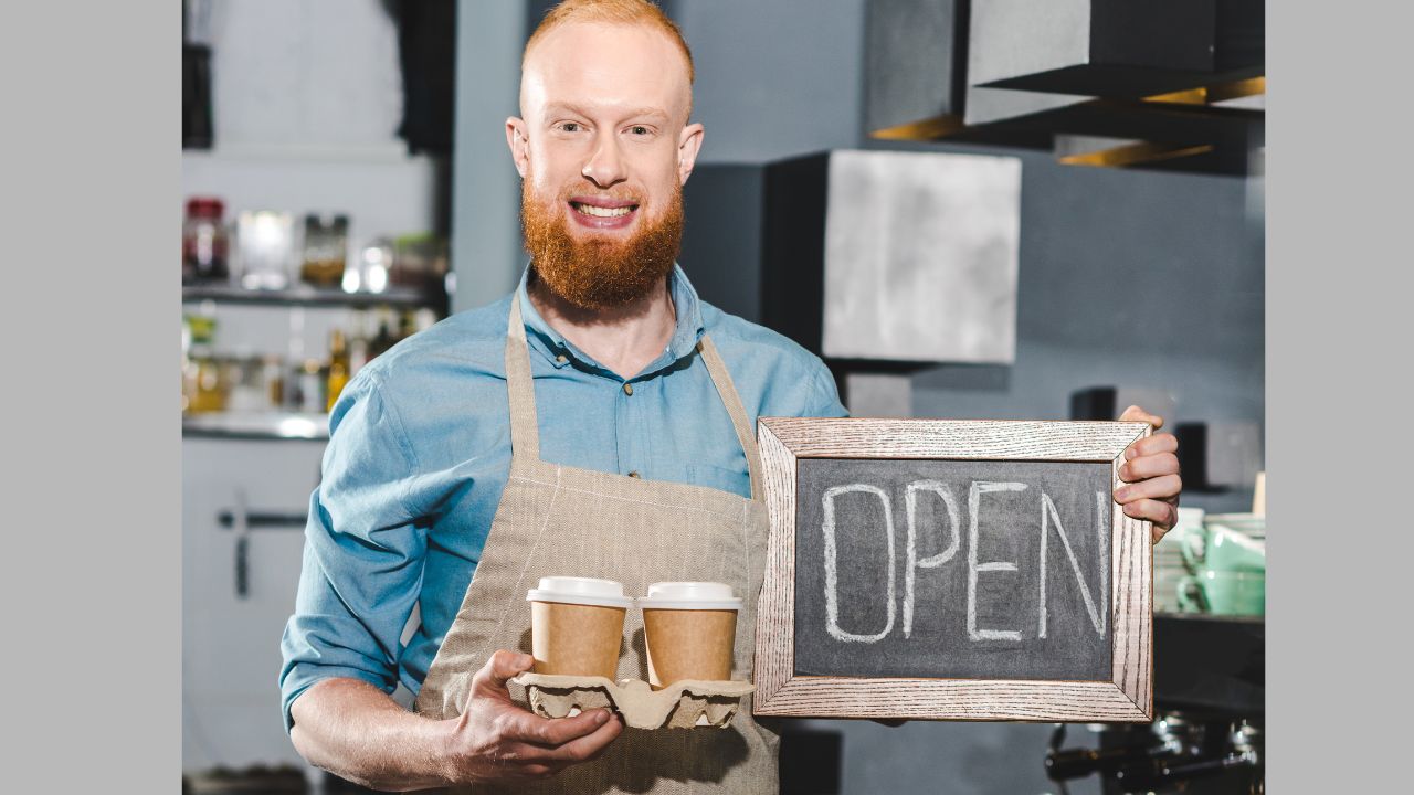 barista or coffee shop owner holding an open sign