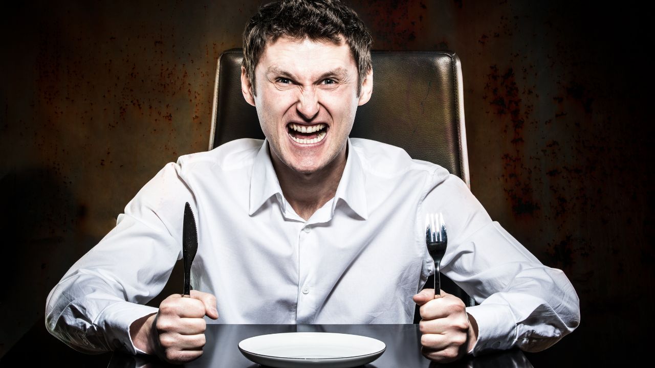 angry man holding knife and fork waiting for food