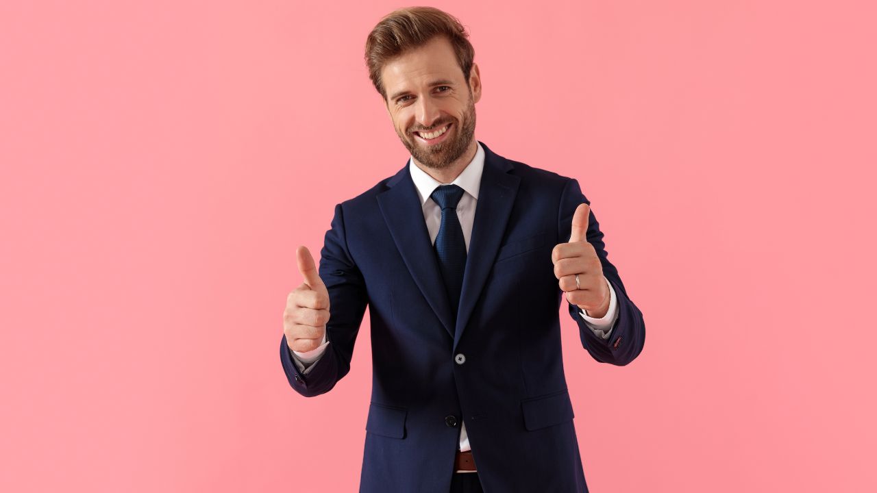 man wearing a suit looking happy and giving two thumbs up