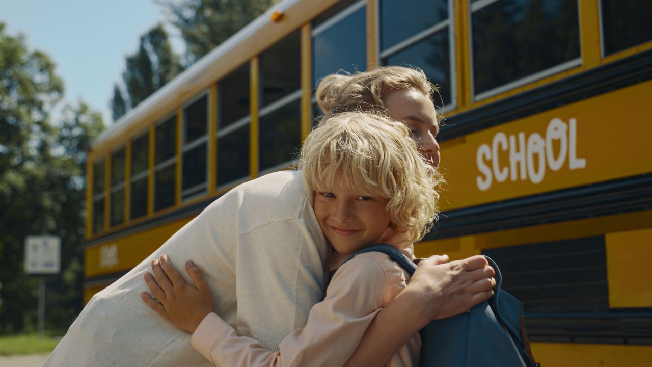 mom hugging child getting on school bus