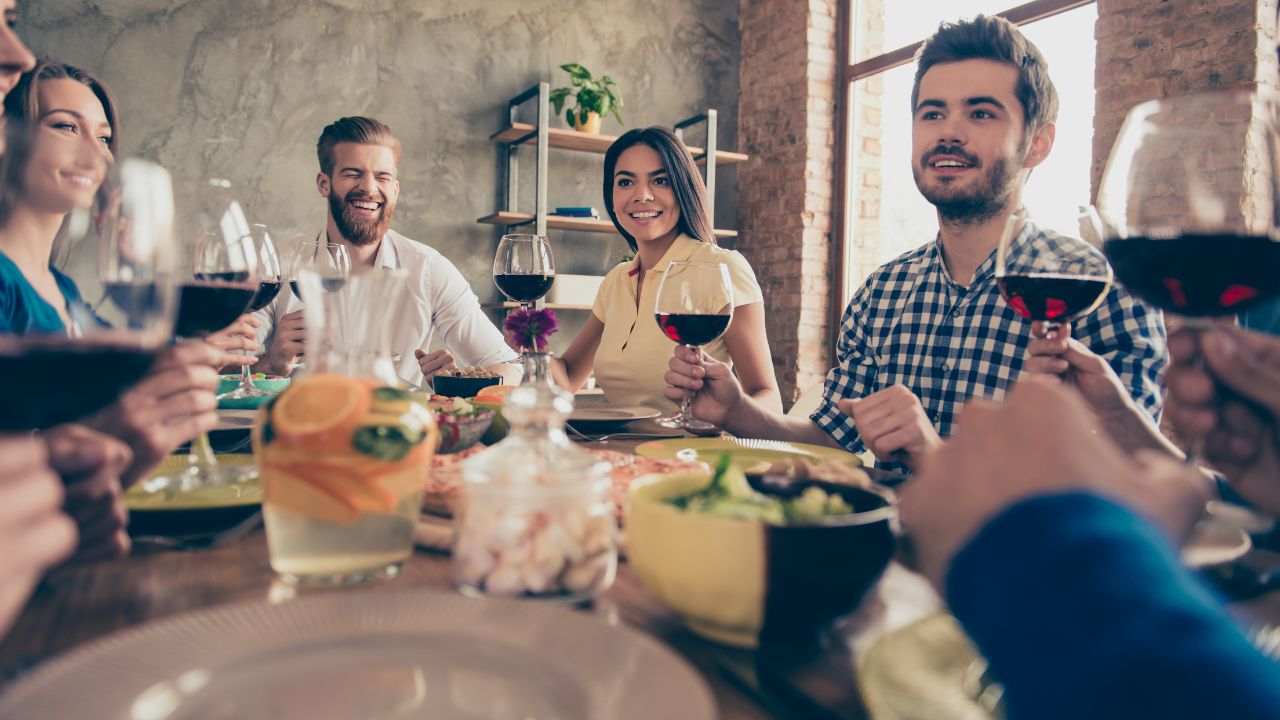 people eating at restaurant together, holding wine glasses up