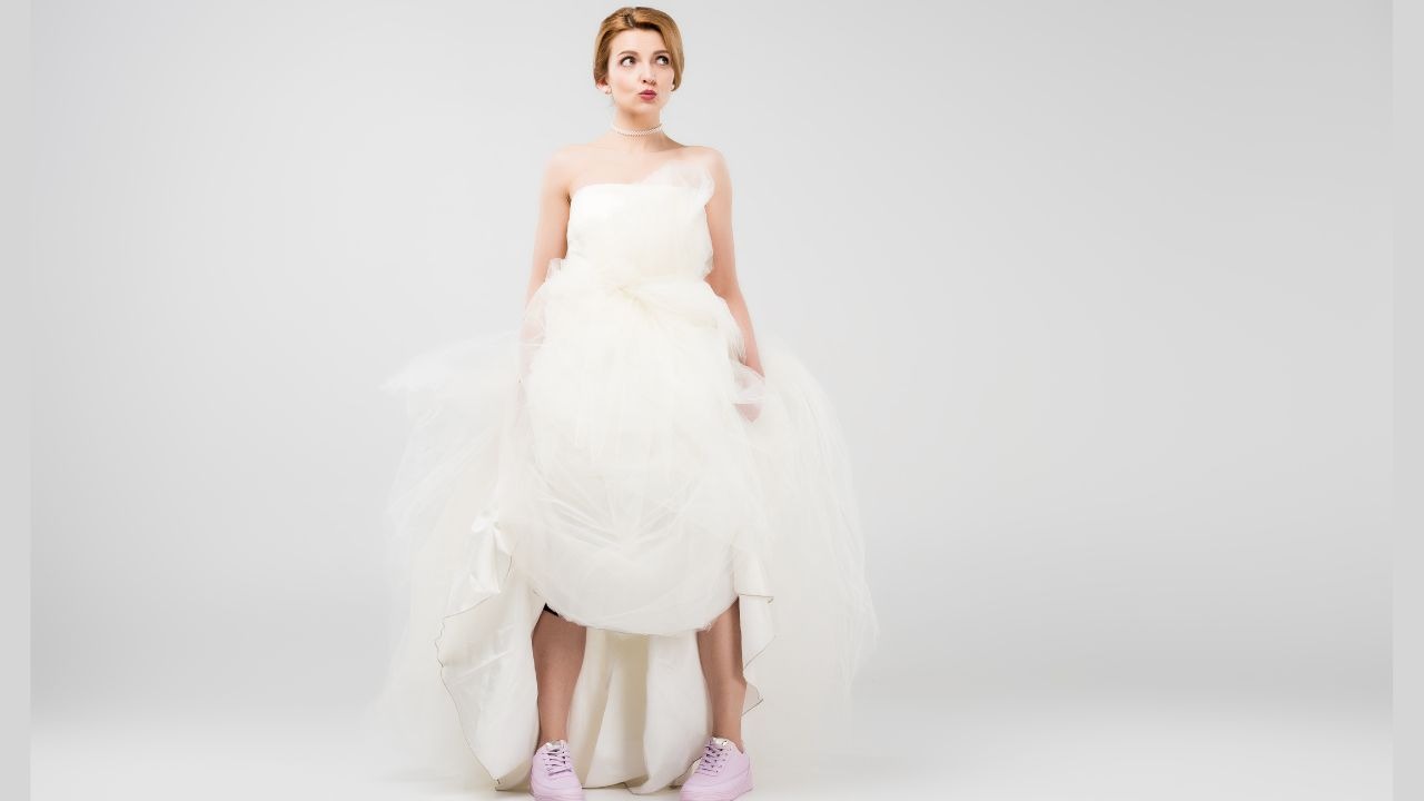 woman looking nervous as she wears a white wedding dress with pink shoes