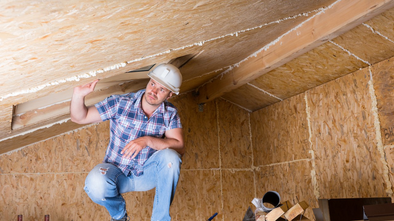 contractor man in the unfinished attic of the house