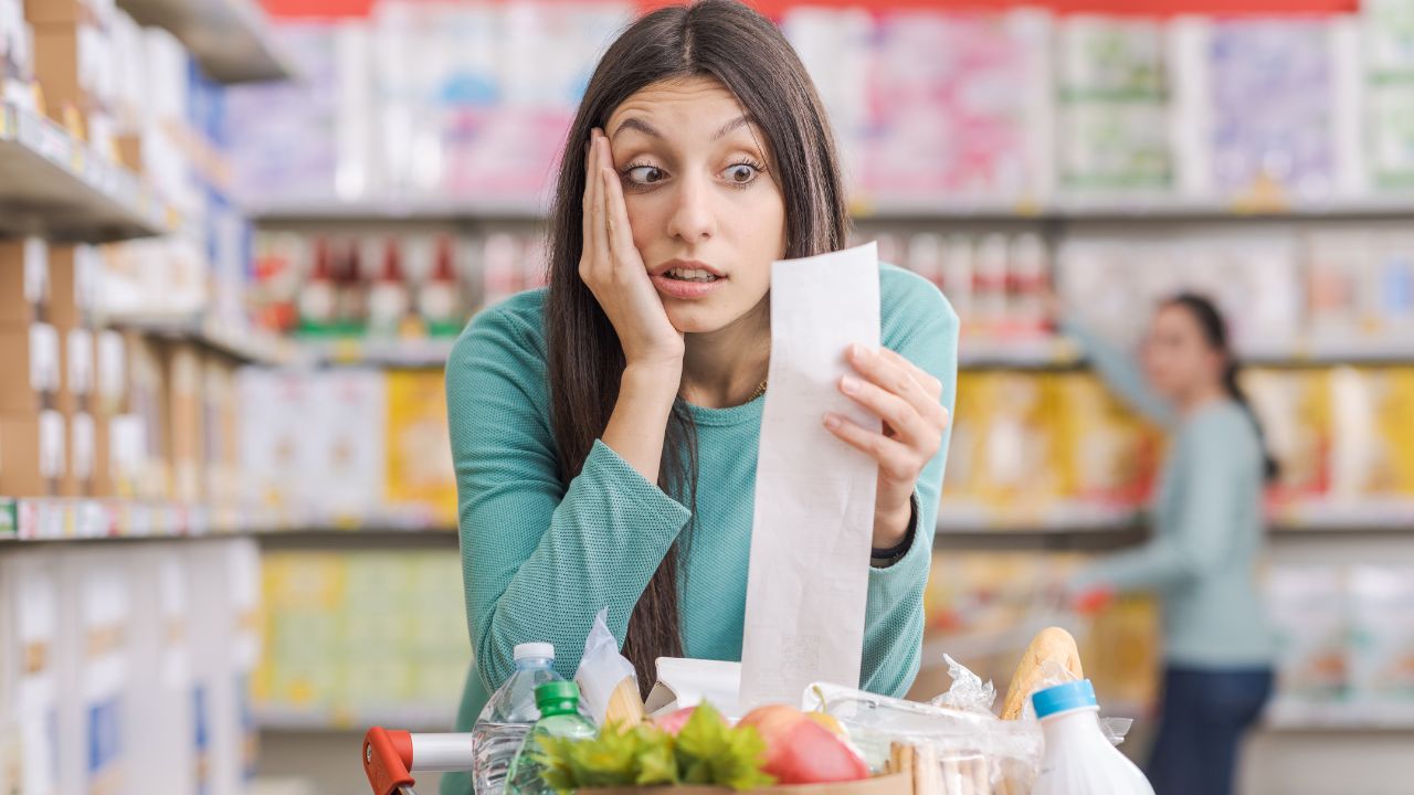 woman upset looking at receipt in grocery store, too expensive, no money