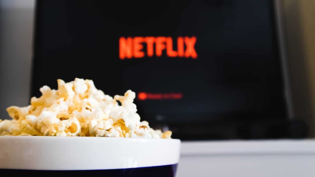 Netflix on a television screen in the background and bowl of popcorn