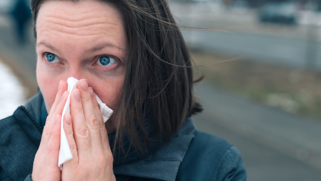 Woman outside in the cold blowing nose