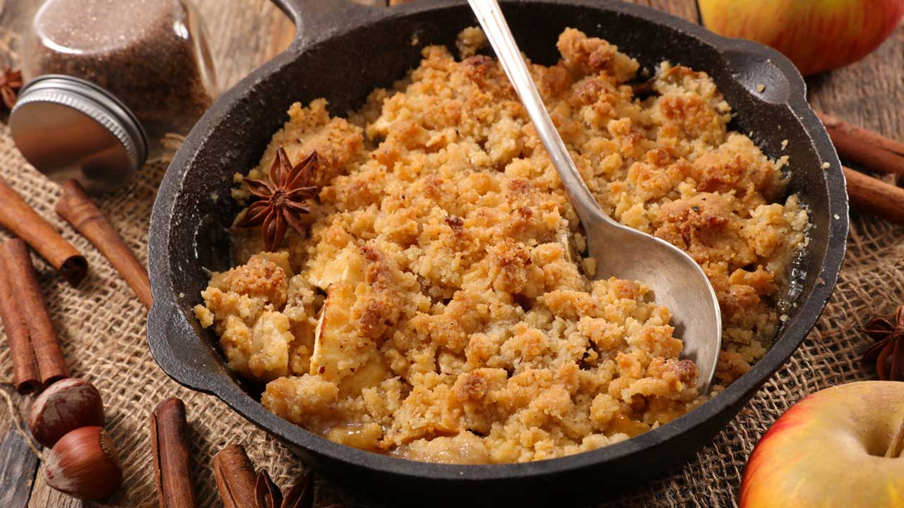 apple crumble in a skillet with a spoon on top