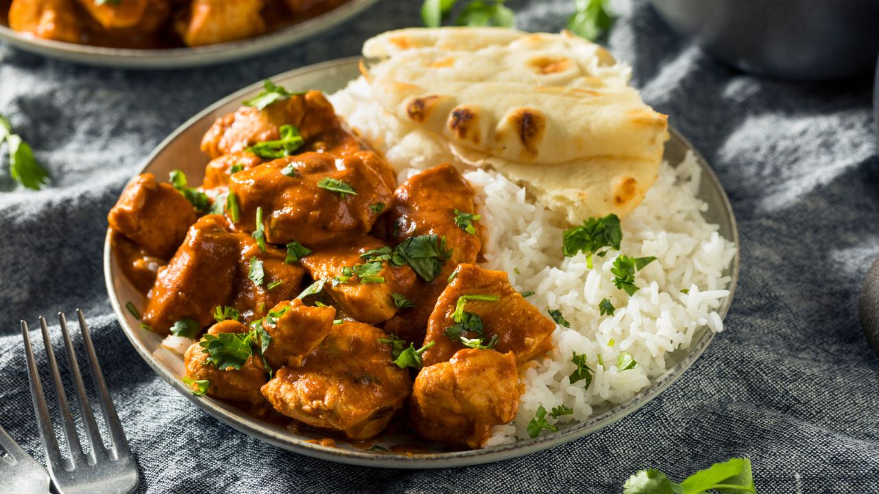 chicken tikka masala on a plate with rice and naan