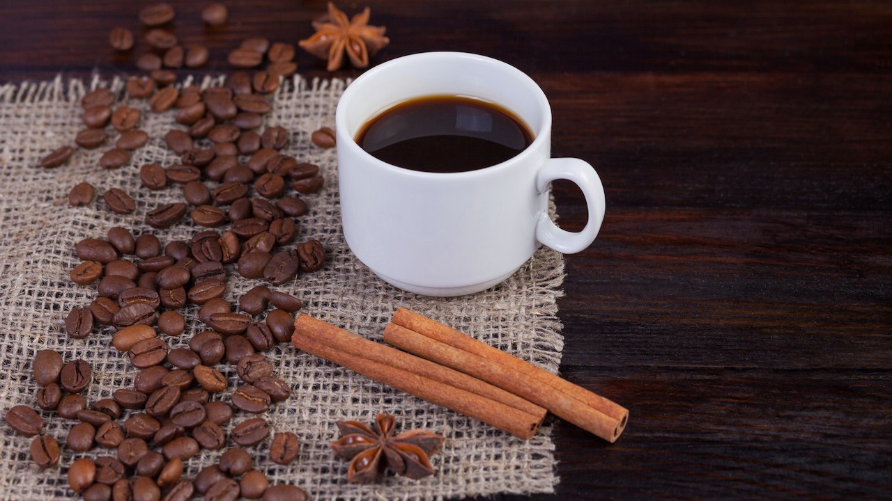Cup of coffee beside ground beans