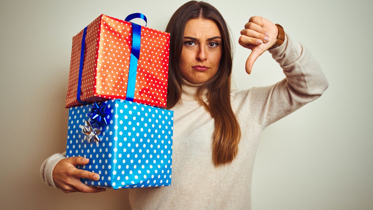 woman holding two gifts and giving thumbs down for overspending