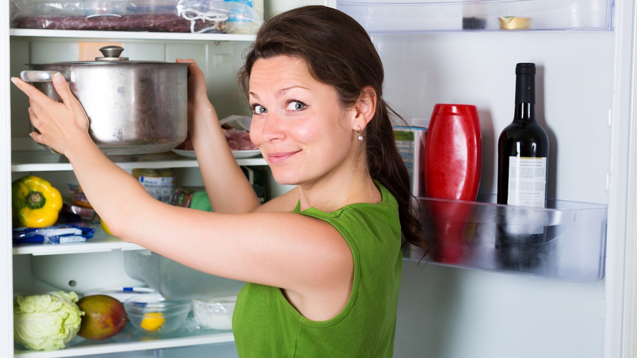 Woman putting a pot in the fridge