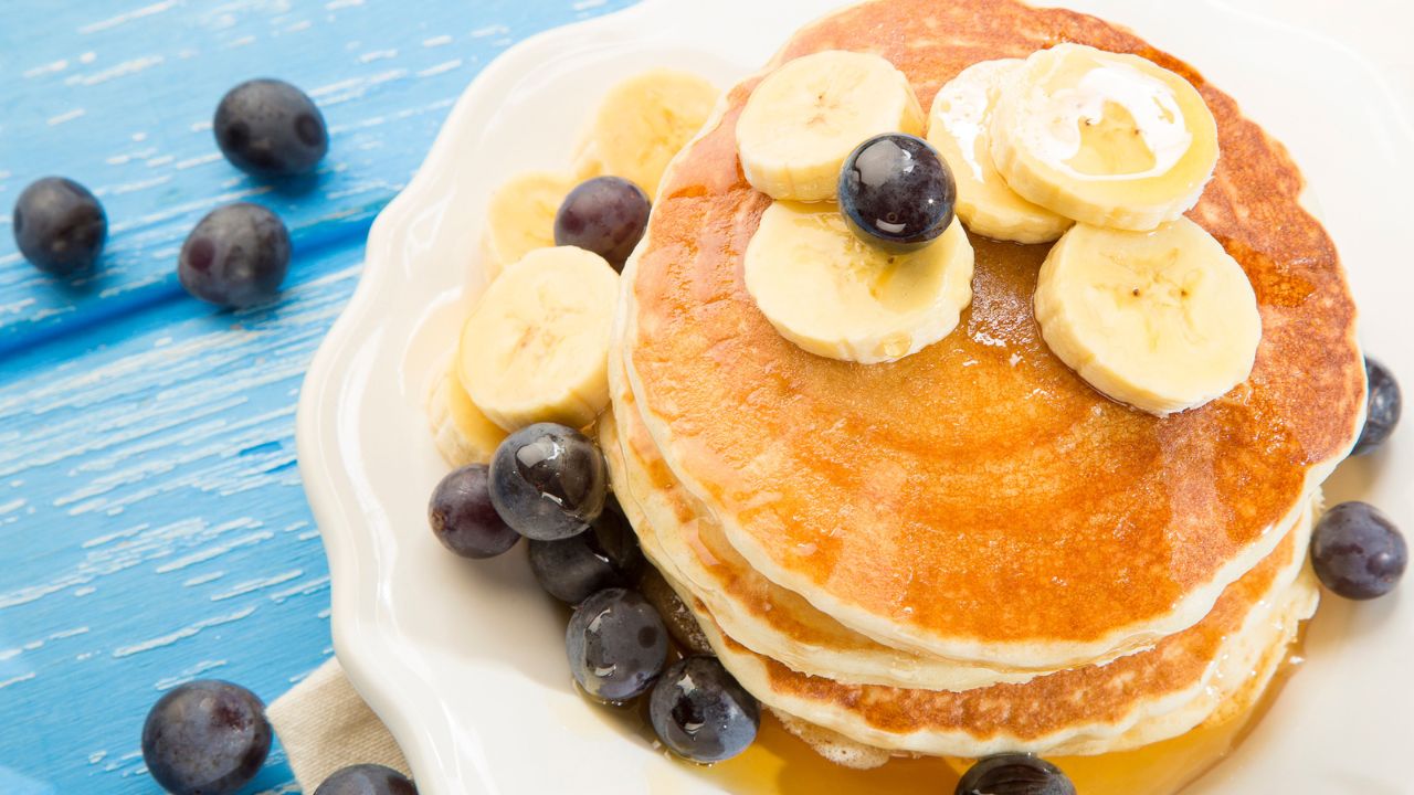 banana pancakes on a plate with blueberries and banana slices on top