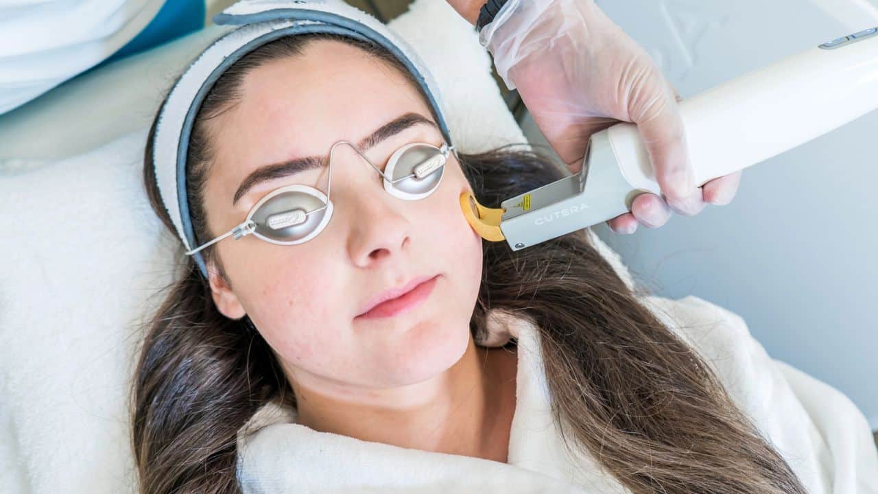 woman lying down with special glasses getting laser treatment